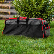 Grey and red Roamwild Carry-More wheeled bag on a garden lawn